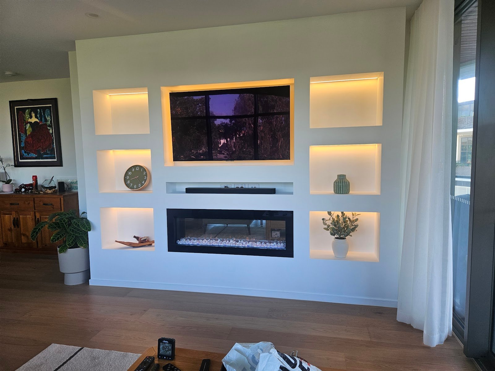Custom living room media wall with electric fireplace and warm LED display niches built by Yushin Kim
