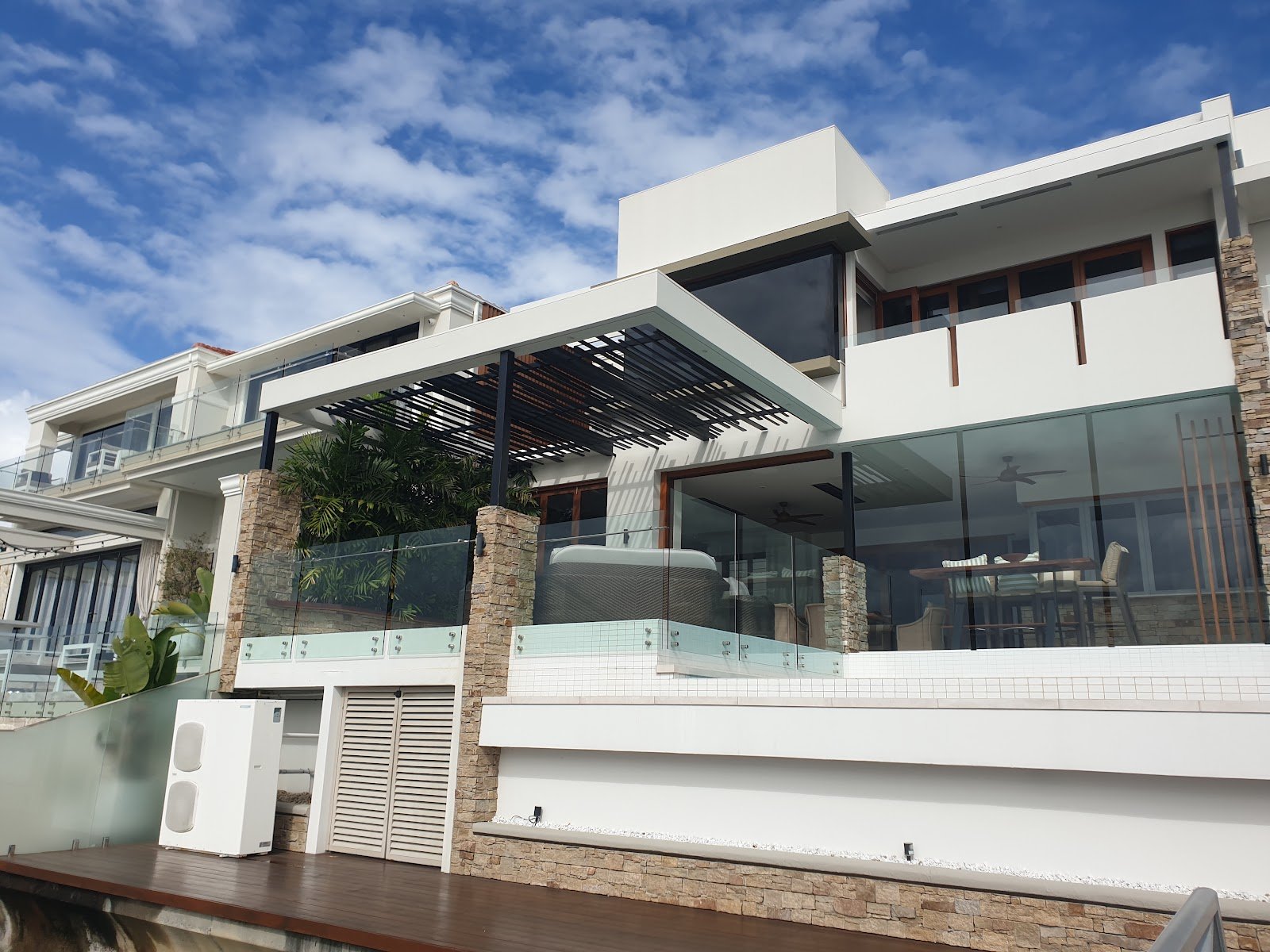 Waterfront luxury mansion featuring timber pergola and hardwood decking by Yushin Kim